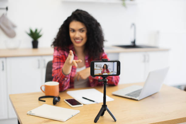 istock Young woman recording video blog in modern kitchen using smartphone setup 2204271292