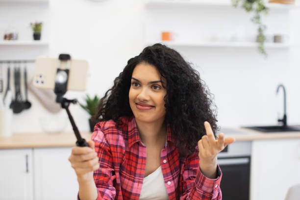 istock Happy young woman taking selfie on kitchen using smartphone and tripod 2204271305