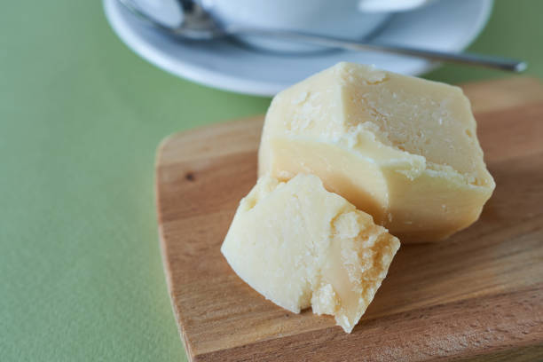 Parmesan cheese on a wooden plank on a green background.