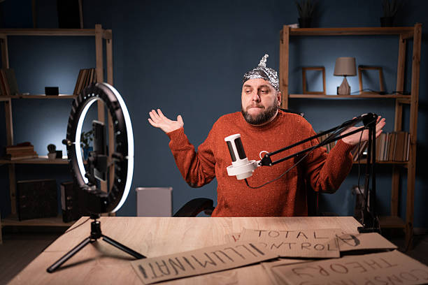 istock Crazy conspiracy theorist blogger streaming live at home using smartphone and ring light, showing gesture, I don't know 2204276181