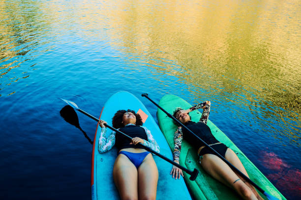istock Two young women relaxing on paddle boards in a lake during sunset 2204276536