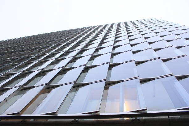 A bottom view of the glass facade tall building. Look at the skyscraper windows from the bottom