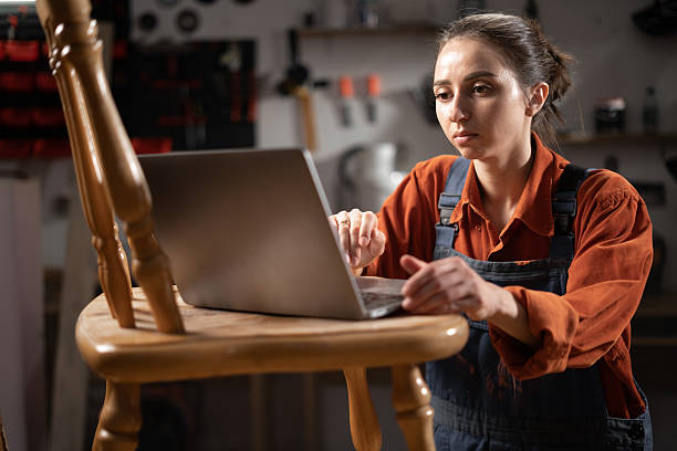 istock Carpenter small business owner craftswoman using laptop in her workshop 2204276843