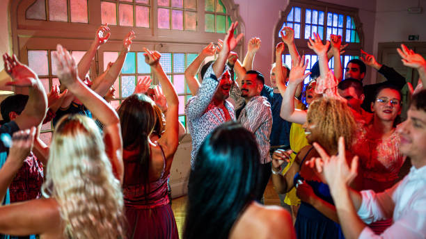 Diverse Dance Enthusiasts Celebrate in Vibrant Studio Lighting A lively group of diverse dance enthusiasts, men and women, joyfully celebrating in a brightly lit dance studio with colorful lighting and energetic movements. Perfect Event Venue stock pictures, royalty-free photos & images