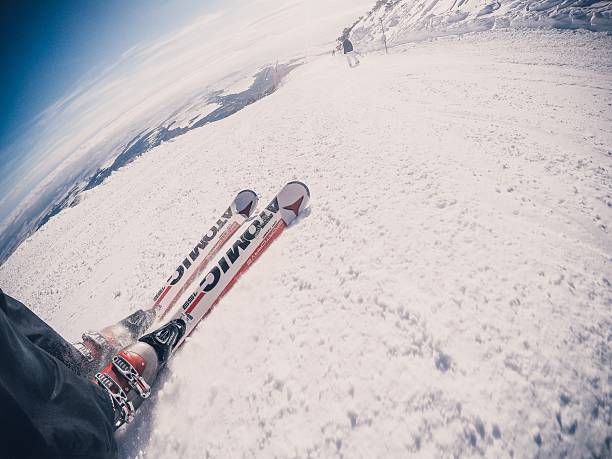 Kosice, Slovakia – August 03, 2016: A skier's perspective with skis on a snowy mountain slope under a clear blue sky, capturing the thrill of skiing.