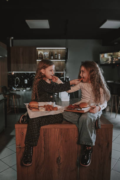 istock Girl share burger with her sister 2204285518