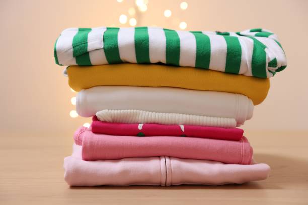istock Stack of folded clothes on wooden table against beige background 2204286293