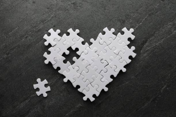 Heart made of puzzles with missing piece on black table