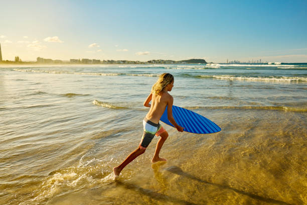 latin child boy with surfboard on the beach in Mexico Latin America, hispanic people surfing in summer sport activity