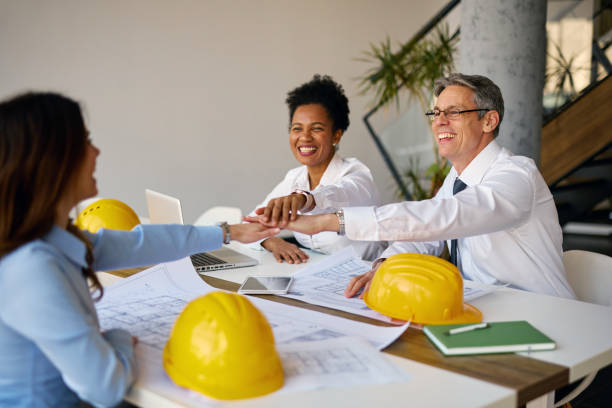 istock Architects joining hands over blueprints in the office 2204288430