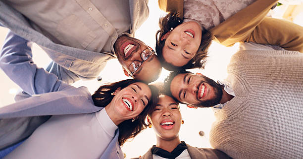 istock Happy group, portrait and huddle with team below for motivation, unity or mission together. Low angle, faces or excited people with smile, hug or support for community solidarity, trust or synergy 2204289651