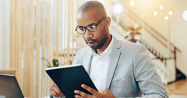 istock Research, online and black person with tablet, serious and app for user experience and web designer. Reading, digital and man with device for design trends, planning and professional in business 2204290963