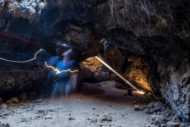 istock A ghostly figure appears within the dimly lit cave, created by the long exposure technique capturing movement over time. A single beam of light streams down from an opening above, illuminating the rocky floor with an ethereal glow 2204293894
