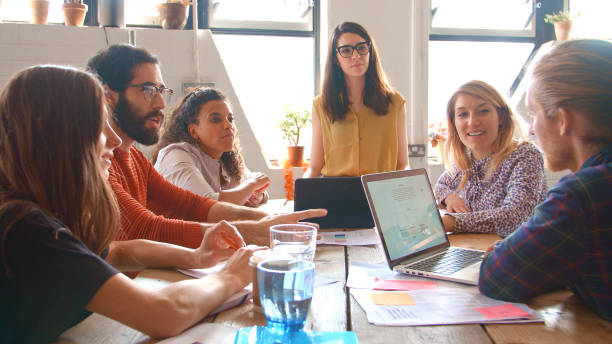 istock Multi-Cultural Business Team Meeting Around Table In Office With Laptop And Documents 2204296467