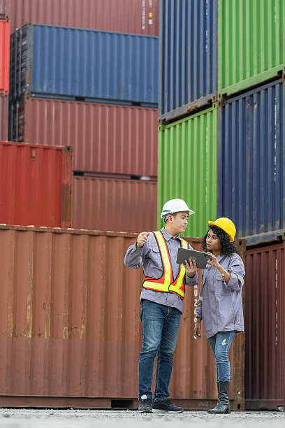 istock Supervisor in safety gear and foreman worker in hardhat checking and control loading containers box from shipping yard 2204296513