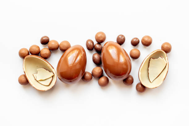Broken and whole chocolate egg on white background, top view. Chocolate background.