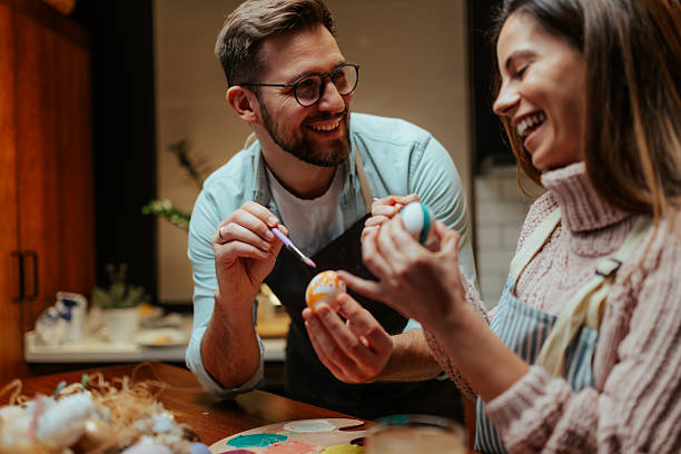 istock Young couple enjoying easter egg painting activity together at home 2204305296