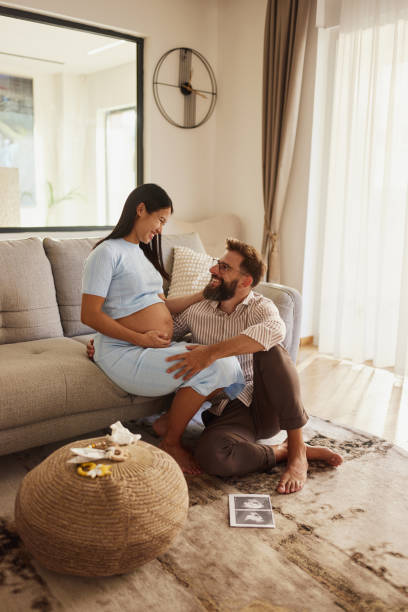 istock Happy expecting couple talking on sofa at home. 2204305755