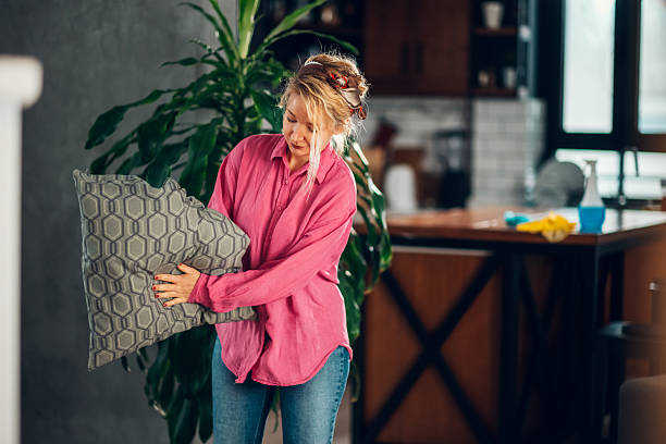 istock Woman fluffing pillow in modern kitchen 2204307348