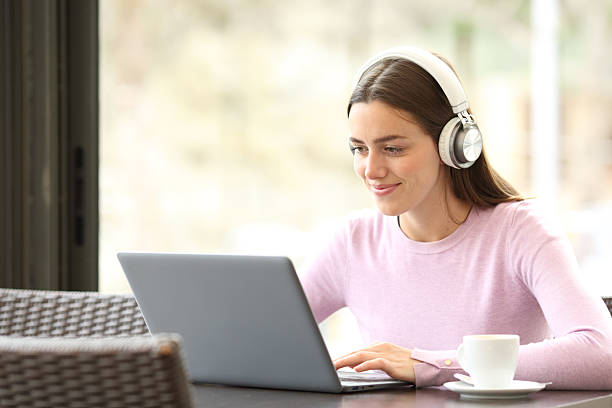 istock Relaxed woman in a restaurant using laptop and headphone 2204312796