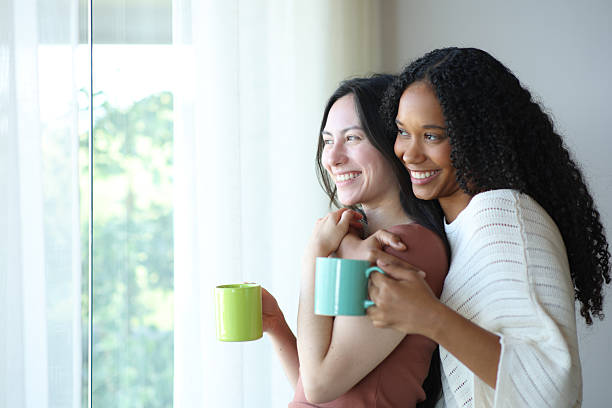 istock Happy interracial lesbian couple drinking and hugging 2204313488