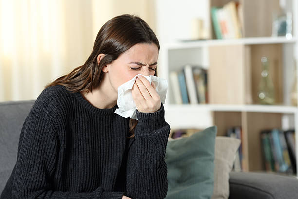 istock Ill woman blowing nose at home 2204313982