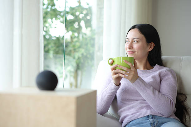 istock Relaxed asian woman drinking beside a smart speaker 2204314732