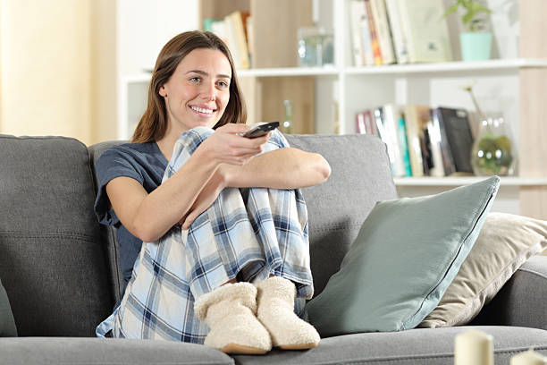 istock Happy woman at home watching tv using remote control 2204314799