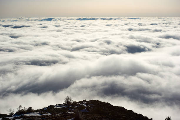 A mountain peak in Pyrenees, France, partially covered with fog