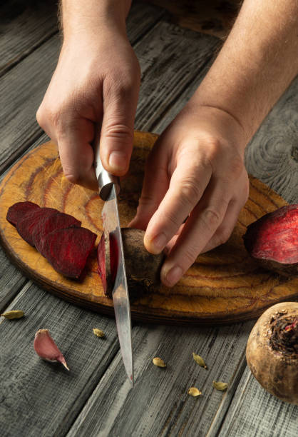 istock Hands carefully slice beets on a wooden cutting board, surrounded by fresh vegetables, showcasing a moment of food preparation in a cozy kitchen setting 2204317108