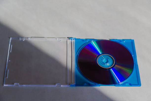 A case with a compact disc is lying in the sun on a gray tabletop, close-up. An old format of digital media. Technologies that have lost relevance, vintage technology.