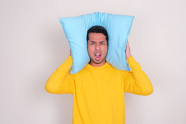 istock A man screaming panic while cover his ears with pillow 2204325073