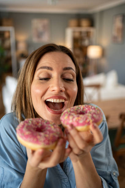 istock Happy woman holding two pink donuts at home 2204325766
