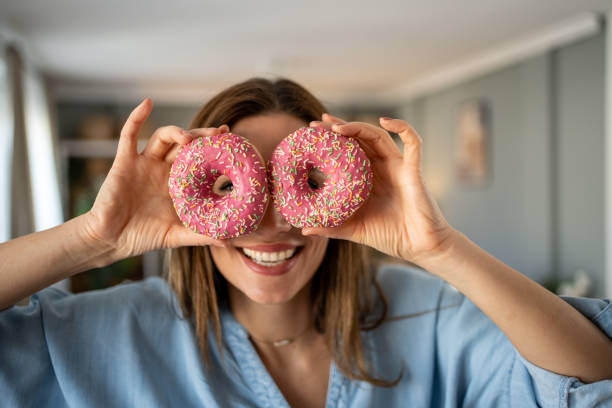 istock Playful young woman holding two pink donuts over eyes 2204325784