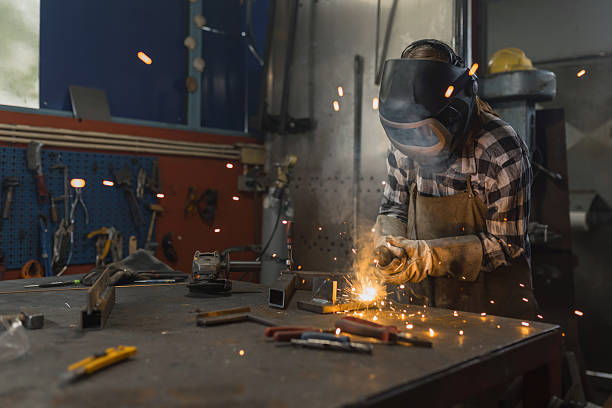 istock Sparks, hot steel particles getting on the camera while a woman welder welding 2204326428