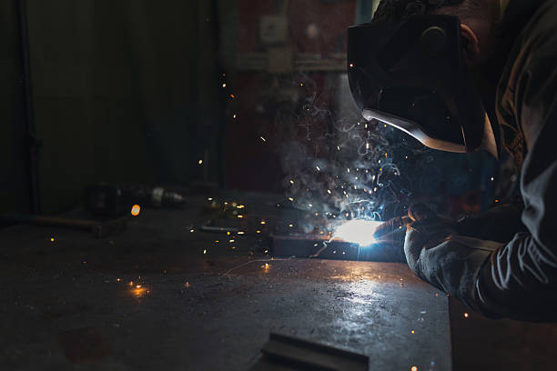 istock Male welder using a welding machine producing bright sparks, flashes and fume 2204326578