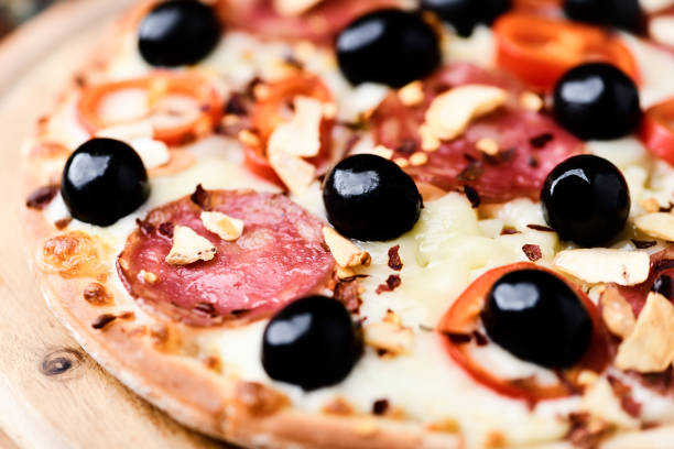 Pizza with salami and mozzarella cheese. Wooden background. Soft focus. Close up.