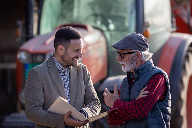 istock Bank agent talking to farmer on farm about contract 2204327473
