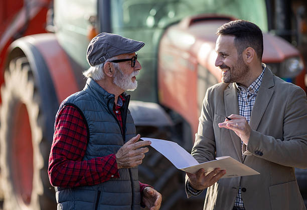 istock Bank agent talking to farmer on farm about contract 2204327480