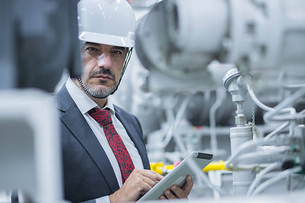 istock Professional engineer inspecting machinery in an industrial facility while using a tablet for data analysis 2204328749