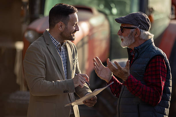 istock Bank agent talking to farmer on farm about contract 2204329502