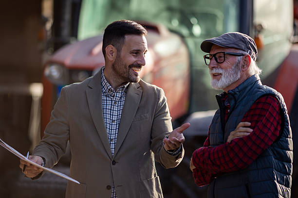 istock Bank agent talking to farmer on farm about contract 2204329503