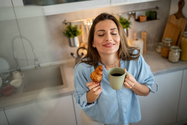 istock Woman enjoying coffee and croissant in kitchen 2204332613