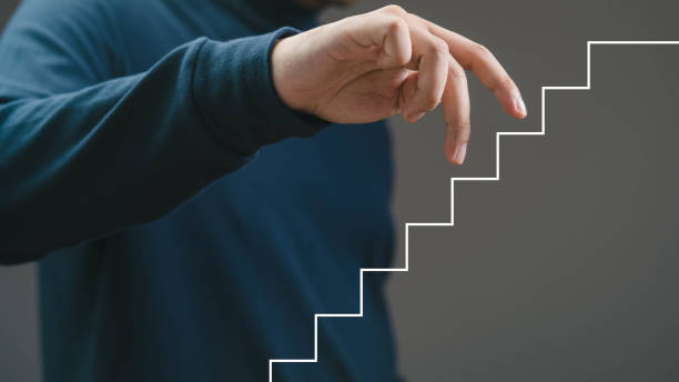 istock A close-up of a hand reaching towards a creative graphic staircase, symbolizing progress and growth in a professional environment. 2204333922