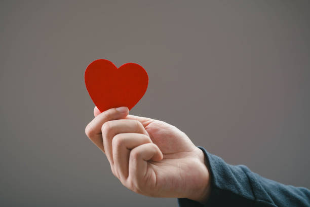 istock A hand holding a vibrant red heart shape against a neutral background, symbolizing love, affection, and connection in everyday life. 2204333989
