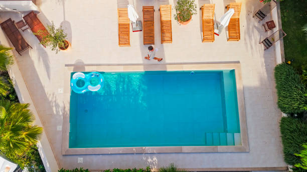 istock Mature Man Walking by Serene Poolside with Lounge Chairs and Greenery in Sunlit Setting 2204336915