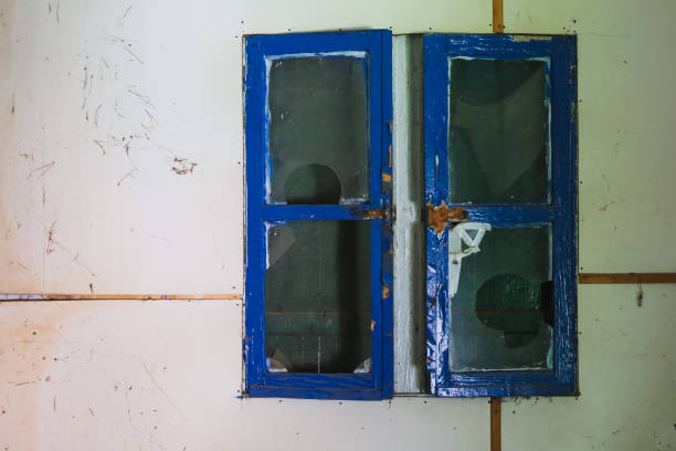 close-up of an old wooden window with a partially open blue shutter on a weathered wall