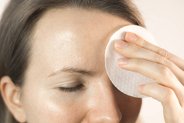istock Woman wipes forehead with toner pads. Clarifying tissues for clogged pores. Moisturizing effect with acids. Anti-wrinkle therapy. Close up. 2204337447