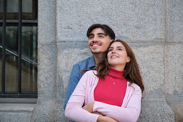 Happy young couple embracing and looking up with hope and smiling