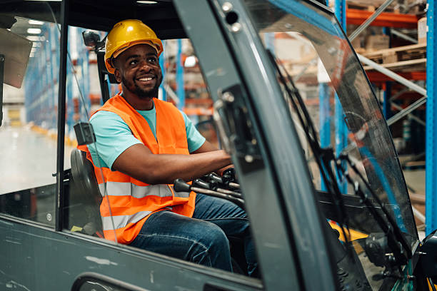 istock Warehouse worker driving forklift and smiling in logistics center 2204342365